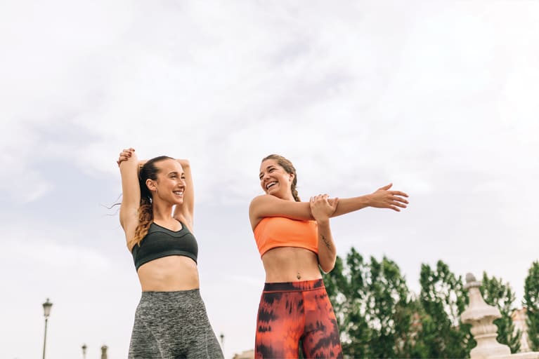 two women stretching outside in athleisure two women stretching outside in athleisure