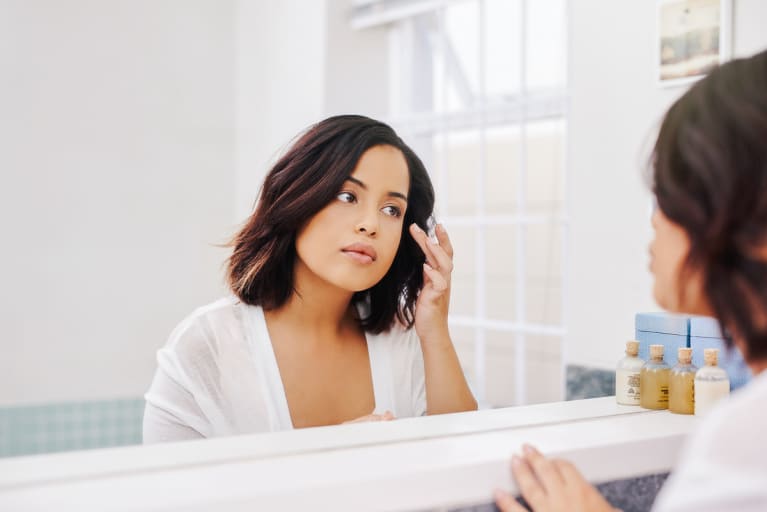 Woman Checking Her Skin in the Bathroom Mirror