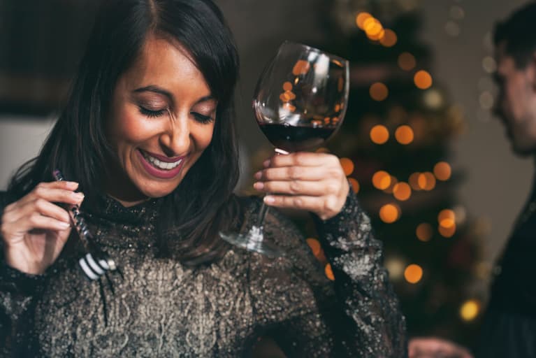 women at holiday party holding wine glass