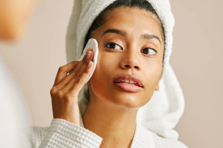 Woman in a Robe and Towel Using a Cotton Pad with Facial Toner