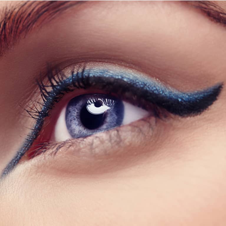 Closeup shot of a woman's eye highlighted with blue eyeliner and mascara