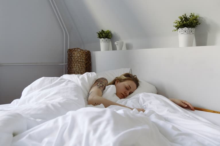 young woman sleeping in white bedroom with plants over bed young woman sleeping in white bedroom with plants over bed