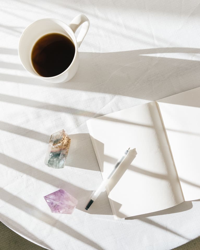 Crystals On Table With Coffee Cup, Pen, And Notebook Crystals On Table With Coffee Cup, Pen, And Notebook