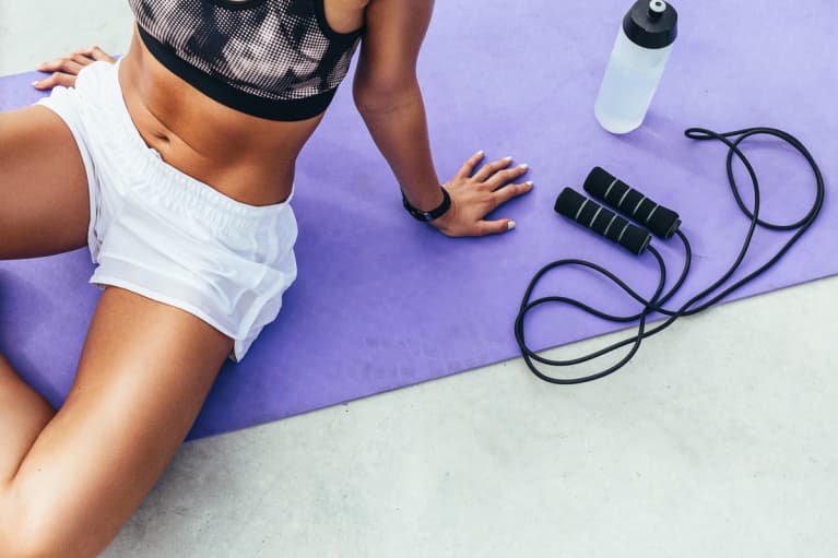 Unrecognizable Woman on a Pilates Mat with Water Bottle and Jumprope