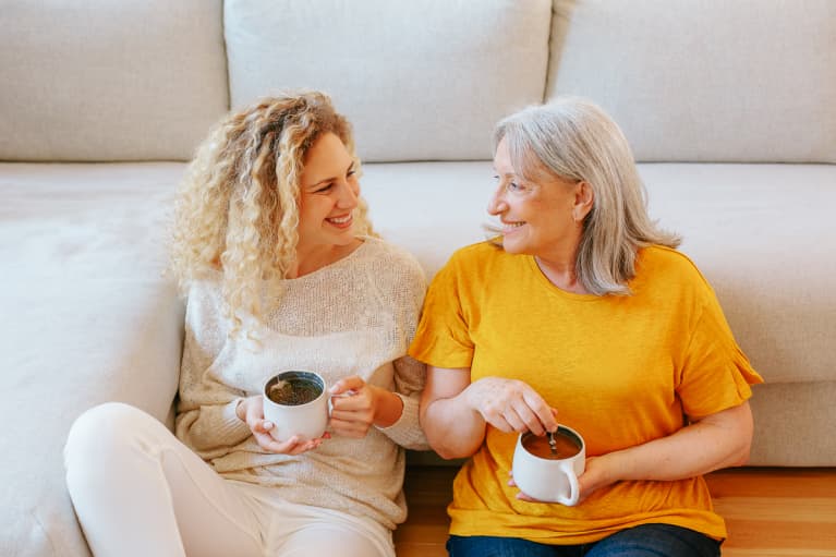 Mother and daughter smiling together holding a cup of tea