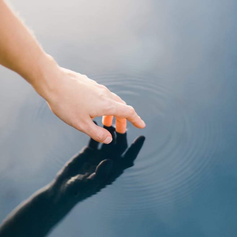 Hand Reaching to Touch Still Water