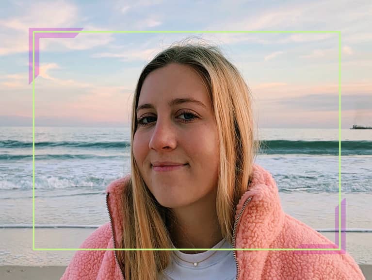 Blonde girl wearing a pink fuzzy jacket and a white tshirt, standing in front of an ocean Blonde girl wearing a pink fuzzy jacket and a white tshirt, standing in front of an ocean