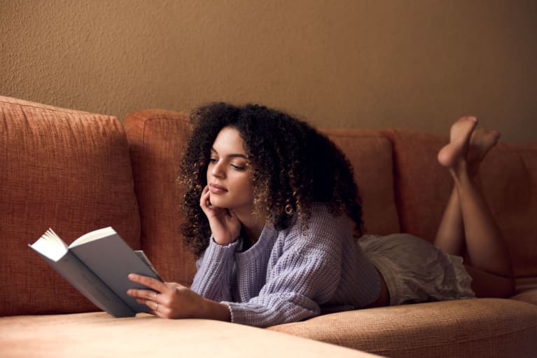 woman laying on couch reading