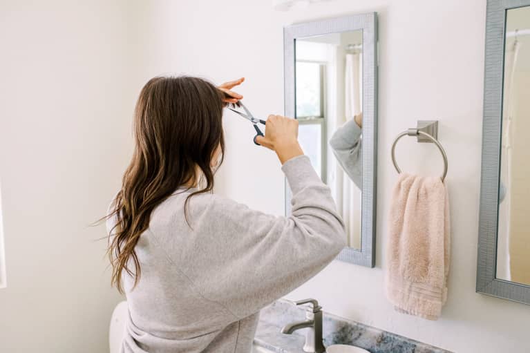 Woman Trimming Her Bangs in the Bathroom Mirror