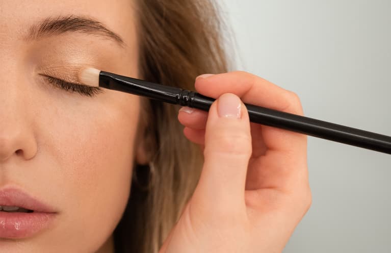 woman applying eyeshadow with makeup brush