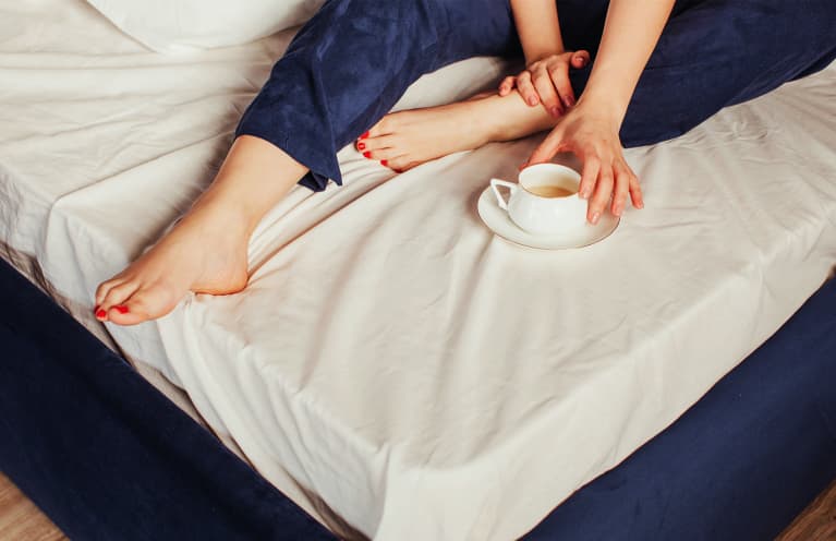 Woman With Cup Of Coffee On Bed showing toes Woman With Cup Of Coffee On Bed showing toes
