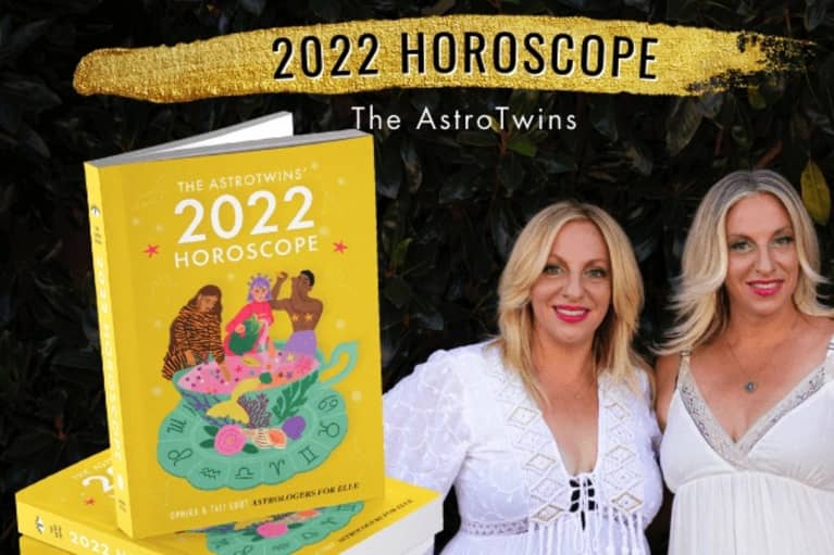 two astrologers wearing white next to a stack of their horoscope book 
